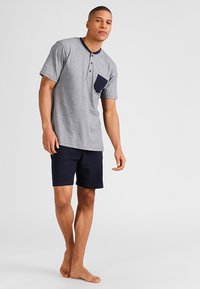 Grijze korte mouwen shirt met navy kraag en zak, gecombineerd met navy shorts, gemaakt van zachte stof, met een relaxte pasvorm.