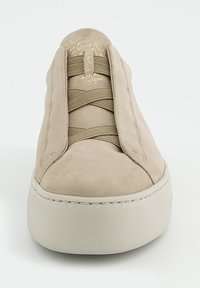 Beige Wildleder-Sneaker mit elastischen Schnürsenkeln, runder Zehenpartie und strukturierter weißer Gummisohle. Goldene Beschriftungen auf der Zunge setzen Akzente.