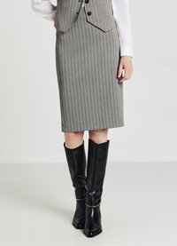 Jupe crayon gris à rayures fines avec une coupe ajustée, associée à des bottes en cuir noires à talons hauts ornées de détails en argent.