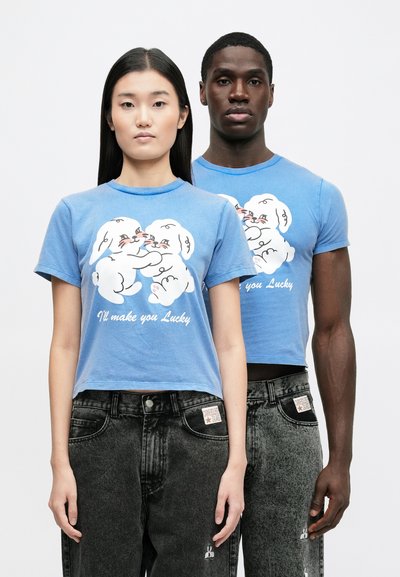 Μπλε κοντομάνικα μπλουζάκια με γραφικό καρτούν κουνελιού και κείμενο, συνδυασμένα με σκούρα τζιν τζιν με μικρό λογότυπο κουνελιού στην τσέπη.