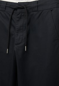 Black pants with a drawstring waist, featuring a smooth texture, side pockets, and metallic tips on the drawstring.