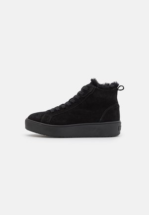 Black suede high-top sneaker with thick sole, lace-up front, fur trim inside collar, and pull tab at the heel.
