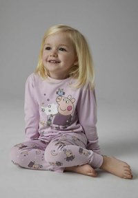 Ensemble de pyjama violet clair avec un personnage de dessin animé portant une lanterne sur la tête et des motifs ludiques d'étoiles et de différents animaux sur le pantalon.