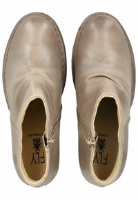 Botas de tobillo de cuero beige con una textura suave. Con cremalleras a los lados, punteras redondeadas y un detalle de costura en contraste. Logo visible en el interior.