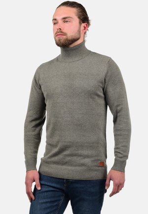 Sivi turtleneck pulover napravljen od pletene tkanine s rebrastim manžetama i rubom. Sadrži malu smeđu kožnu oznaku na donjem prednjem dijelu.