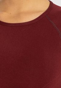 Bourgogne atletisk top med rund halsudskæring, glat tekstur og syede detaljer, der fremhæver et tætsiddende design.