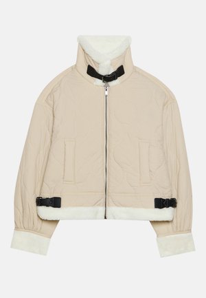 Prešívaná béžová bunda s mäkkým bielym fleecovým golierom a manžetami, s predným zipsom a čiernymi prackovými detailmi. Obsahuje dve predné vrecká.