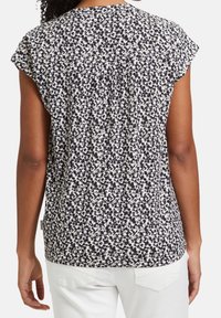 Blommönstrad kortärmad blus i svart och kräm, med en lös passform, plisserad bak och böjd nederkant.