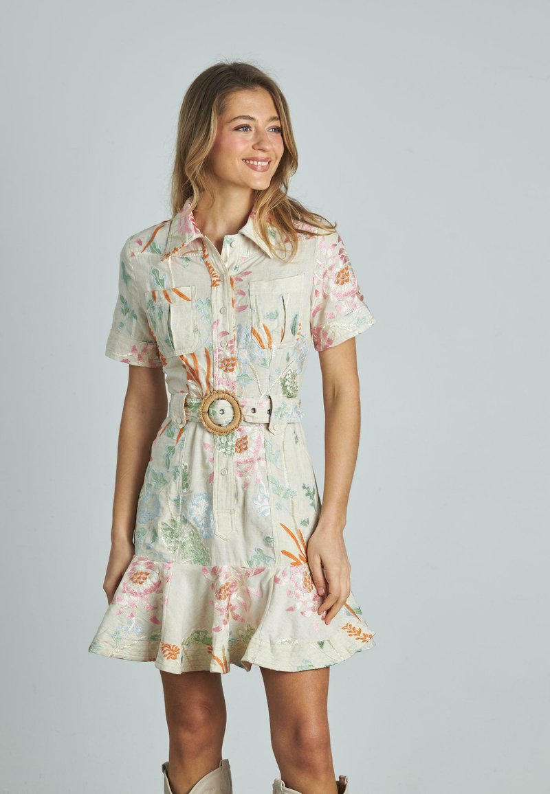 Blumenkleid aus Leinen mit kurzen Ärmeln, Knopfleiste und ausladendem Saum. Verfügt über pastellfarbene Töne, zwei Brusttaschen und einen breiten Gürtel mit einer runden Schnalle.