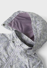 Veste légère à motif floral dans des couleurs pastel avec un intérieur lavande, dotée d'une fermeture éclair intégrale et de fermetures à pression sur la capuche.