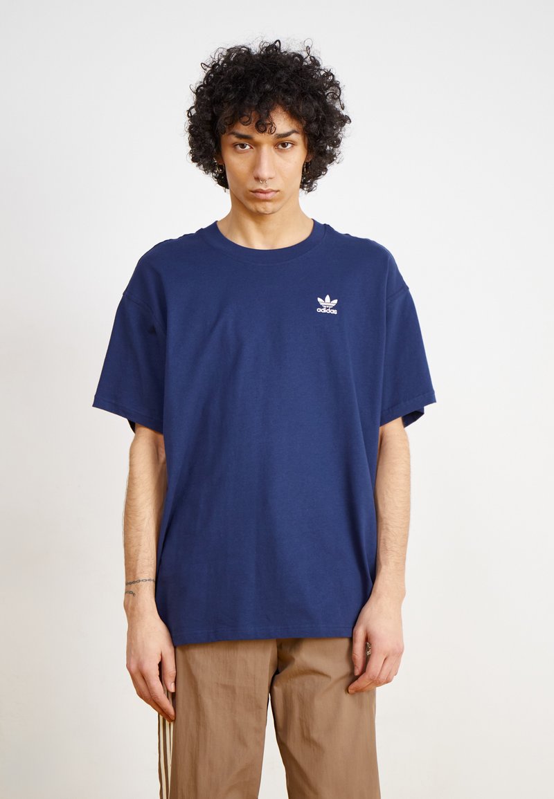 T-shirt en coton bleu marine à manches courtes et col rond. Doté d'un petit logo Adidas blanc sur la poitrine gauche. Coupe douce et décontractée.