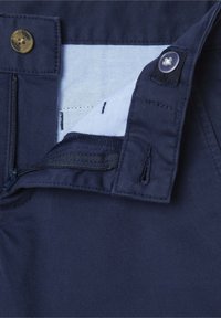 Pantaloni blu navy con chiusura a zip e bottone in ottone, etichetta in tessuto e una texture liscia con dettagli cuciti.