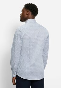 Langärmliges Hemd in Weiß mit einem navyblauen geometrischen Muster. Verfügt über einen klassischen Kragen, geknöpfte Manschetten und ein schlankes Design.