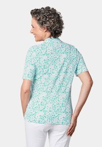 Korte mouwen shirt in lichtblauw met een bloemenpatroon, voorzien van een kraag, knoopsluiting en een soepele stofstructuur.
