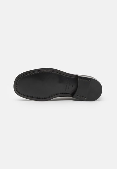 Talpă de pantof din piele neagră, cu vârf rotunjit, textură netedă și detalii de cusătură. Dispune de o bază neagră solidă și de nituțe decorative la toc.