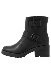 Svarta läderankelpumps med två justerbara spännen, rund tå, strukturerad sula och en kraftig klack för ökad stabilitet.