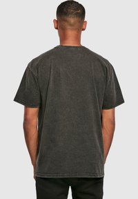 Camiseta de manga corta gris oscuro, fabricada en tela suave, con un corte relajado, cuello redondo y costuras visibles en el dobladillo y las mangas.