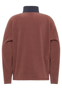 Pull en polaire marron avec un col foncé et des manches longues. Présente un petit logo en relief sur le bas à gauche et des fentes sur les côtés à l'ourlet.