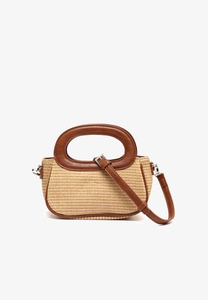 Bolso pequeño rectangular de paja tejida con asa ovalada de cuero marrón y correa ajustable para el hombro sobre fondo blanco.