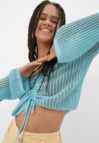 Hellblauer, gestrickter, taillierter Pullover mit offenem Netzdesign, langen Ärmeln und verstellbarem Kordelzug am Saum.