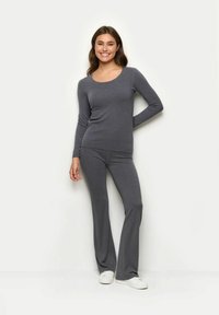 Szary top z długim rękawem i pasujące dzwonowe spodnie z miękkiego materiału. Strój ma dopasowany krój, okrągły dekolt i gładką strukturę.