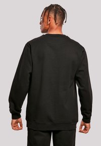 Schwarzes Sweatshirt mit langen Ärmeln, Rundhalsausschnitt und elastischen Bündchen. Weicher Stoff, lockere Passform und schlichtes Design ohne Verzierungen.