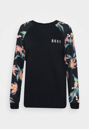 Zwarte trui met bloemenpatroon lange mouwen en de tekst "ROXY" op de linkerborst.