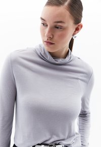 Lichtgrijs langarm T-shirt met een design van een col, gemaakt van zachte stof. Heeft fitted mouwen en een subtiele textuur. Geen patronen of versieringen.