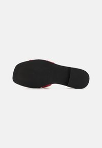 Chaussure rouge avec une semelle noire plate, texture lisse sur le dessus et un design sans couture. Pas de motifs visibles ni de détails matériels.