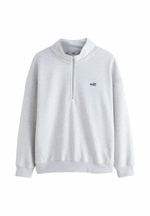 Sweat-shirt gris clair à fermeture quart, avec des poignets et un ourlet côtelés, arborant un petit texte noir "self." sur la poitrine gauche.