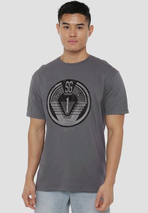 Gray cotton t-shirt featuring a circular graphic design with "SG" and "1" in black, short sleeves, and a crew neck style.