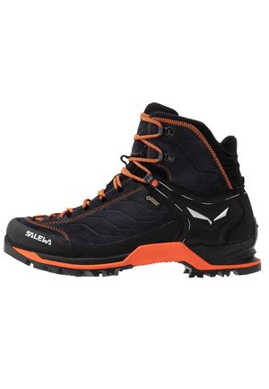 Czarno-pomarańczowy but trekkingowy Salewa z wysokim wsparciem kostki, wytrzymałą podeszwą, pomarańczowymi sznurowadłami i etykietą Gore-Tex zapewniającą wodoodporną ochronę.