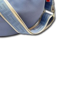 Lichtblauwe leren tas met een gestructureerd oppervlak. Heeft een brede patroontas in blauw met een crèmekleurige rand. Accenten van messing hardware.