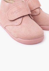 Růžové semišové dětské boty na suchý zip s gumovými podrážkami, detailní záběr zepředu a z boku.