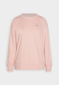 Sudadera rosa claro con cuello redondo, mangas largas y puños acanalados. Presenta un pequeño logo en el pecho y una textura suave y lisa.