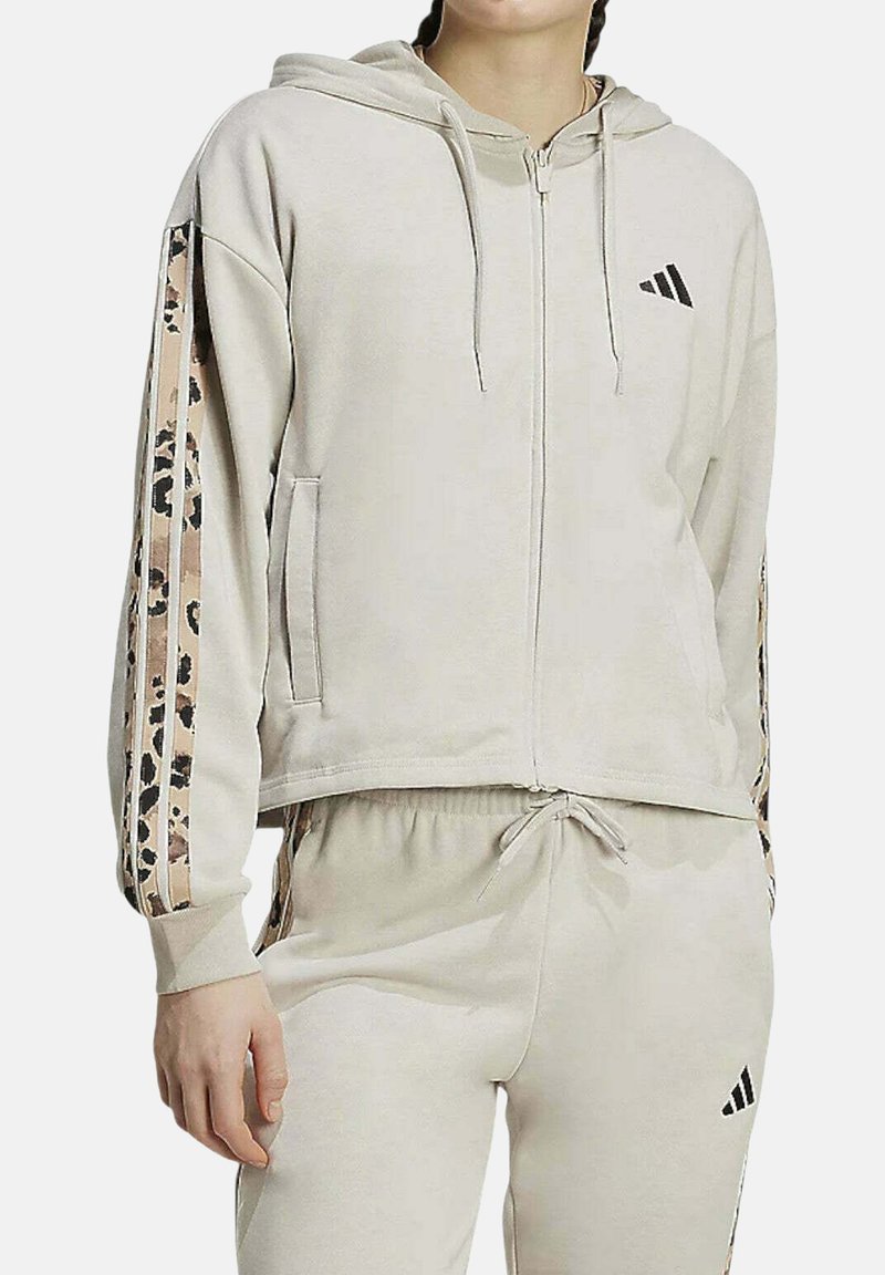 Felpa con zip color beige chiaro, dotata di cappuccio, con strisce laterali leopardate, tasche a marsupio e polsini elasticizzati. Materiale morbido e design cropped.