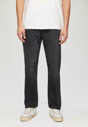 Donkergrijze denim jeans met een recht gesneden pijp, getoond met een wit T-shirt en lichtgekleurde sneakers met grijze accenten.