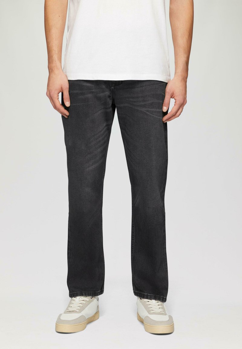 Donkergrijze denim jeans met een recht gesneden pijp, getoond met een wit T-shirt en lichtgekleurde sneakers met grijze accenten.