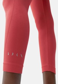 Leggings corallo a vita alta con finitura texturizzata, con un logo argento al polpaccio e una vestibilità aderente intorno alla caviglia.