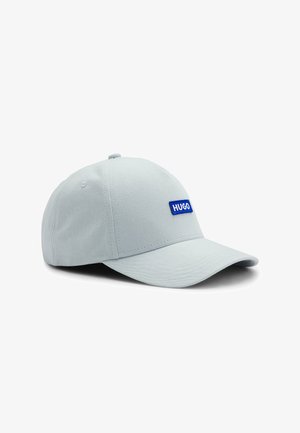 Cappellino da baseball grigio chiaro con visiera curva e una piccola etichetta blu con la scritta "HUGO" sul pannello frontale.