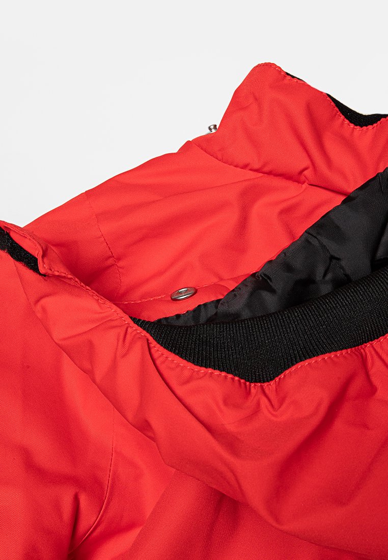 Rote Pufferjacke mit hohem Kragen, ausgestattet mit einem schwarzen Innenfutter und gerippten Bündchen. Mit Druckknopfdetails am Hals.