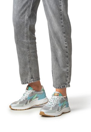 Baskets en mesh et matériaux synthétiques, présentant un schéma de couleurs bleu clair et argenté, avec des accents texturés et une semelle en caoutchouc.