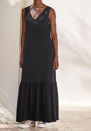 Musta hihaton maksi mekko V-pääntiellä ja kerätty ripsureuna. Yhdistetty kuviollisiin tennareihin. Pehmeä kangas, yksinkertainen malli.