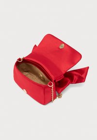 Κόκκινη τσάντα χειρός από σατέν με χρυσό κούμπωμα, λουράκι αλυσίδα και εσωτερικό διαμέρισμα. Το εσωτερικό είναι επενδεδυμένο με μπεζ ύφασμα. Διαθέτει λεπτομέρεια φιόγκο στο πλάι.