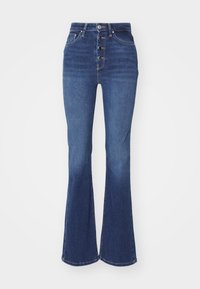 Jean flare en denim bleu foncé avec fermeture à cinq boutons sur le devant, design traditionnel à cinq poches et une finition légèrement délavée au niveau des genoux.