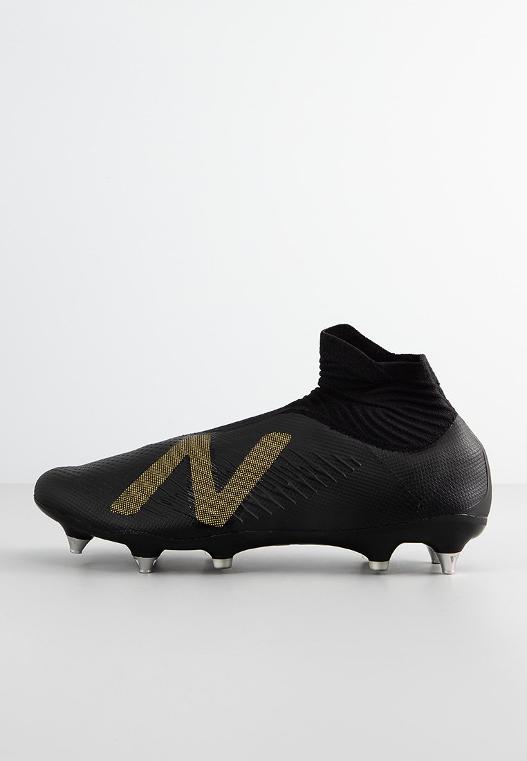 Svart fotbollssko med texturerad design, guld-logotyp och hög krage. Utrustad med formgjutna dobbar för grepp på gräsytor.