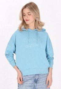 Hoodie azul claro con un corte relajado, que cuenta con un bolsillo canguro y el texto "Felicidad invisible" en una impresión sutil.