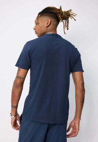 T-shirt en coton bleu marine à manches courtes, col rond et coupe décontractée. Texture lisse, design simple, sans motifs ni accents visibles.