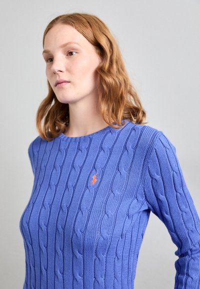 Sinine lõngakootud kampsun, millel on soonikkoes struktuur, ümmargune kaelus ja väike oranž logo ees.