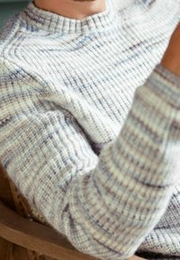 Pull en tricot épais de couleur gris clair avec de subtils rayures bleues. Texture côtelée et encolure ronde. Tissu doux et confortable, idéal pour superposer.